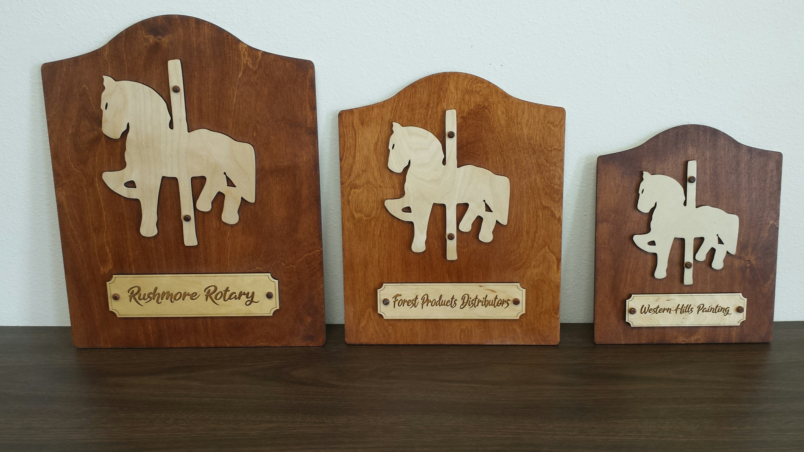 Three wooden Storybook Island donor plaques with layered carousel horse designs